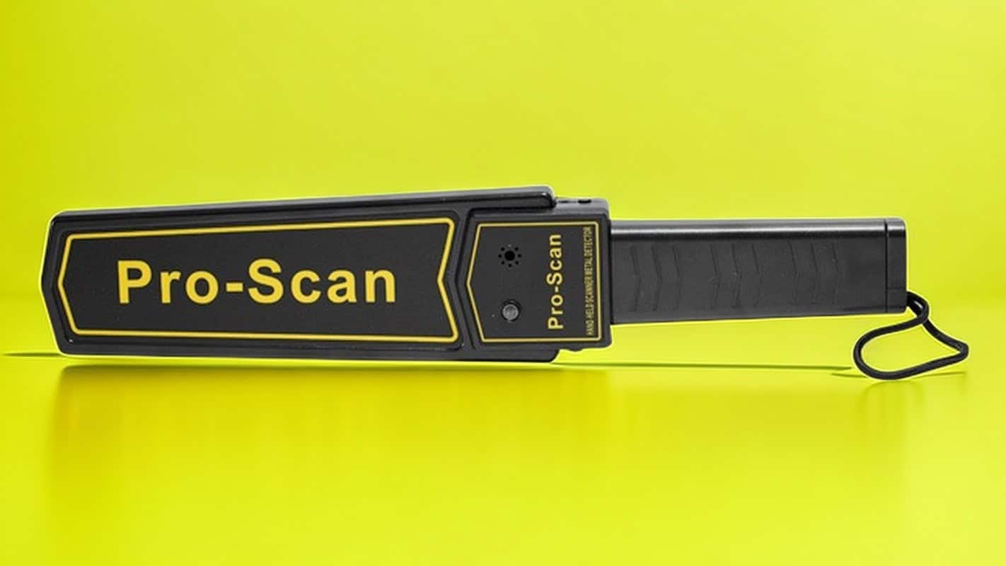 Handheld Pro-Scan metal detector against a bright yellow background.