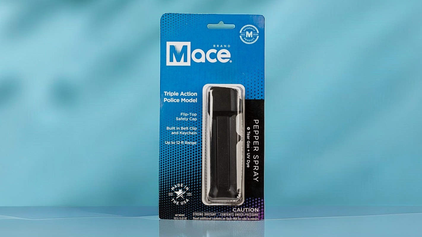 Mace Triple Action Police Model pepper spray with safety cap and belt clip, in packaging on a blue background.