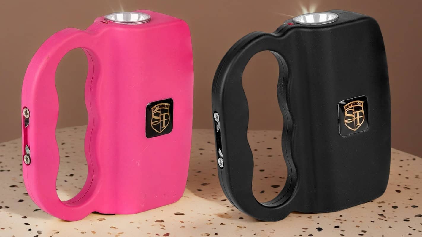 Pink and black self-defense stun devices with LED lights on a speckled surface.