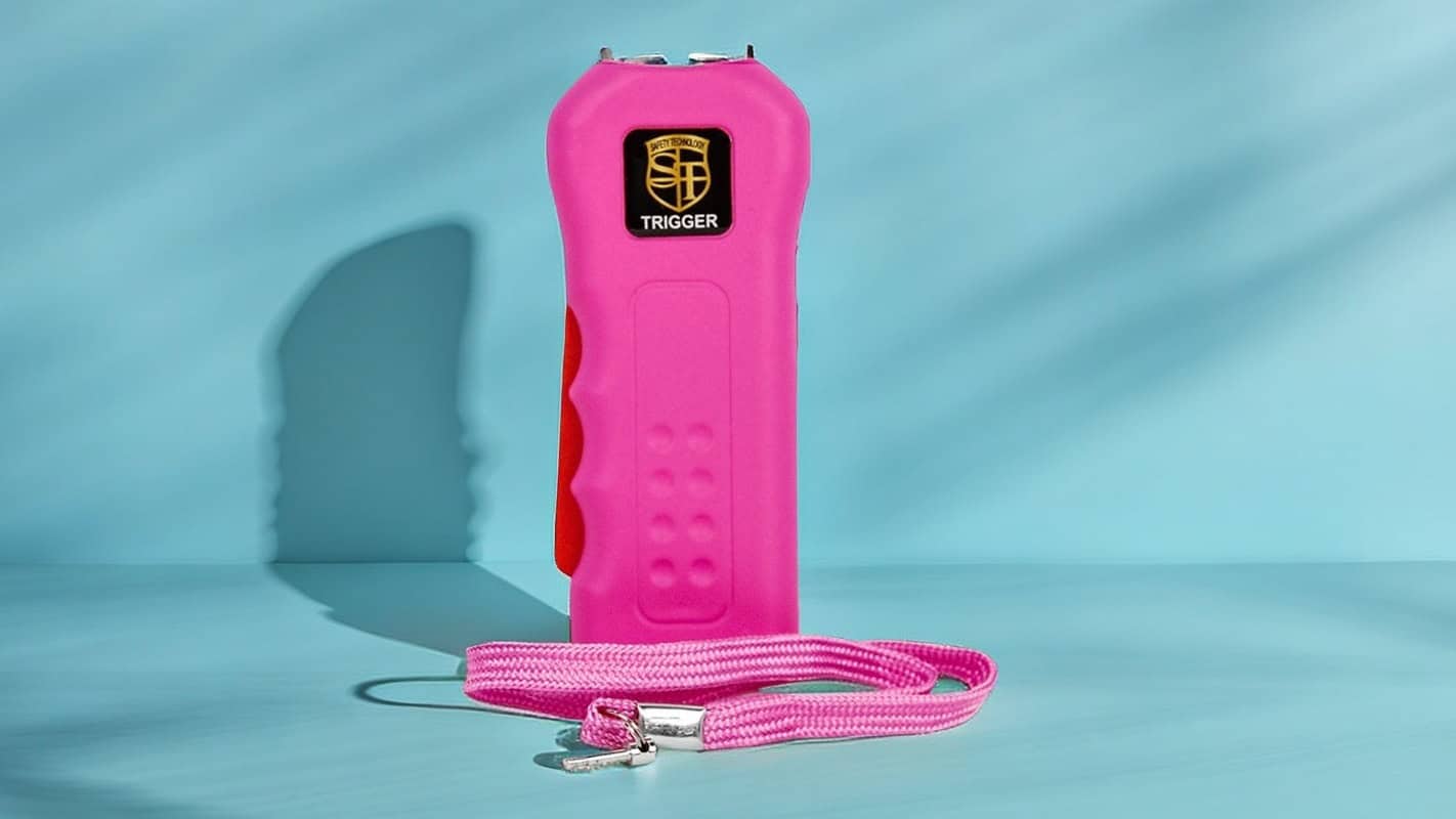 Pink self-defense stun gun with wrist strap on a blue background, featuring ergonomic grip and compact design.